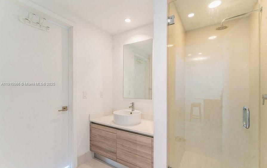 121 Northeast 34th Street, Unit 2811 Miami, FL 33137 - Photo 8 of 35 a bathroom with a granite countertop sink a shower and a mirror