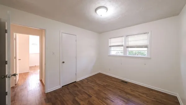 an empty room with wooden floor and windows