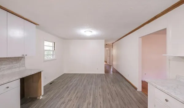 a view of a hallway with wooden floor and a bathroom