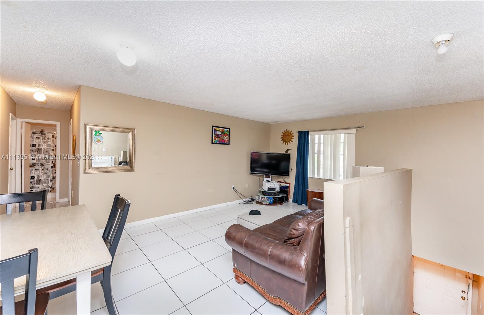 15280 Southwest 80th Street, Unit 11 Miami, FL 33193 - Photo 6 of 13 a living room with furniture a flat screen tv and a refrigerator