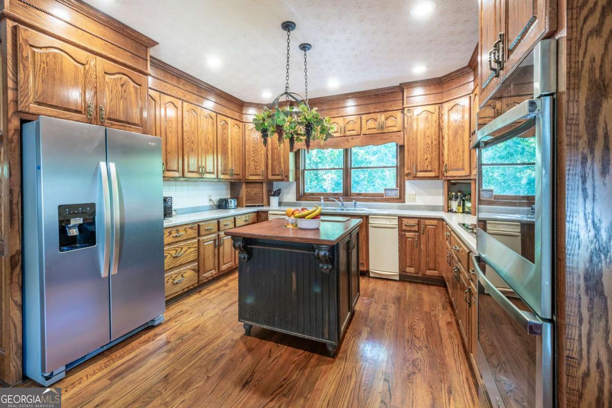 755 Harris Road Jasper, GA 30143 - Photo 28 of 62 a kitchen with stainless steel appliances granite countertop a refrigerator a sink dishwasher a stove and white countertops with wooden floor