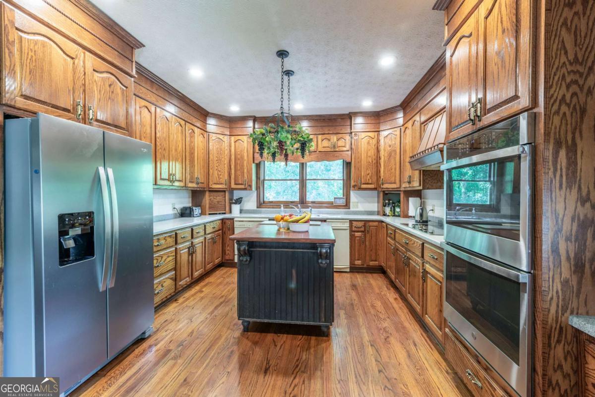 755 Harris Road Jasper, GA 30143 - Photo 29 of 62 a kitchen with stainless steel appliances granite countertop a refrigerator a sink dishwasher a stove and white countertops with wooden floor