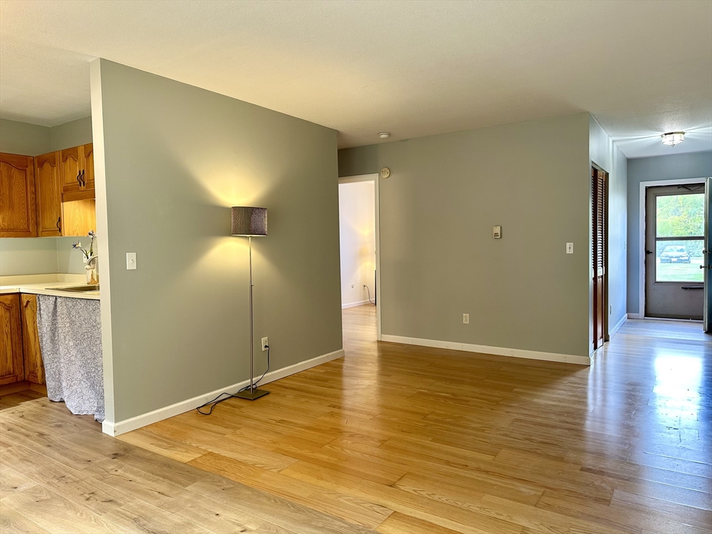 170 East Hadley Road, Unit 11 Amherst, MA 01002 - Photo 5 of 16 a view of an empty room with wooden floor and a window