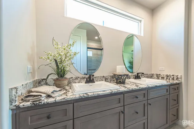 a bathroom with a granite countertop double vanity sink and a mirror