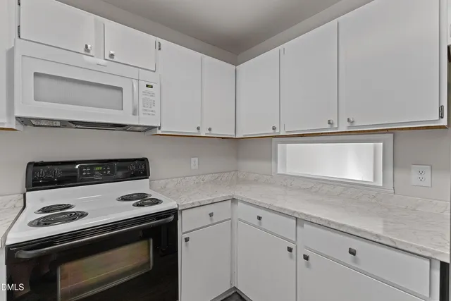 a kitchen with white cabinets and appliances