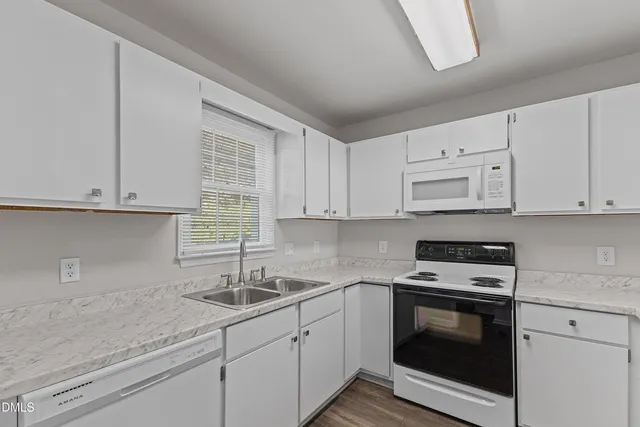 a kitchen with granite countertop white cabinets and white appliances