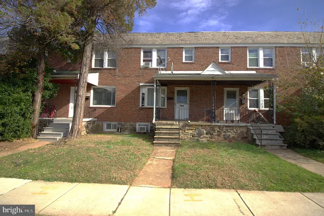 a view of a brick house with many windows and a yard