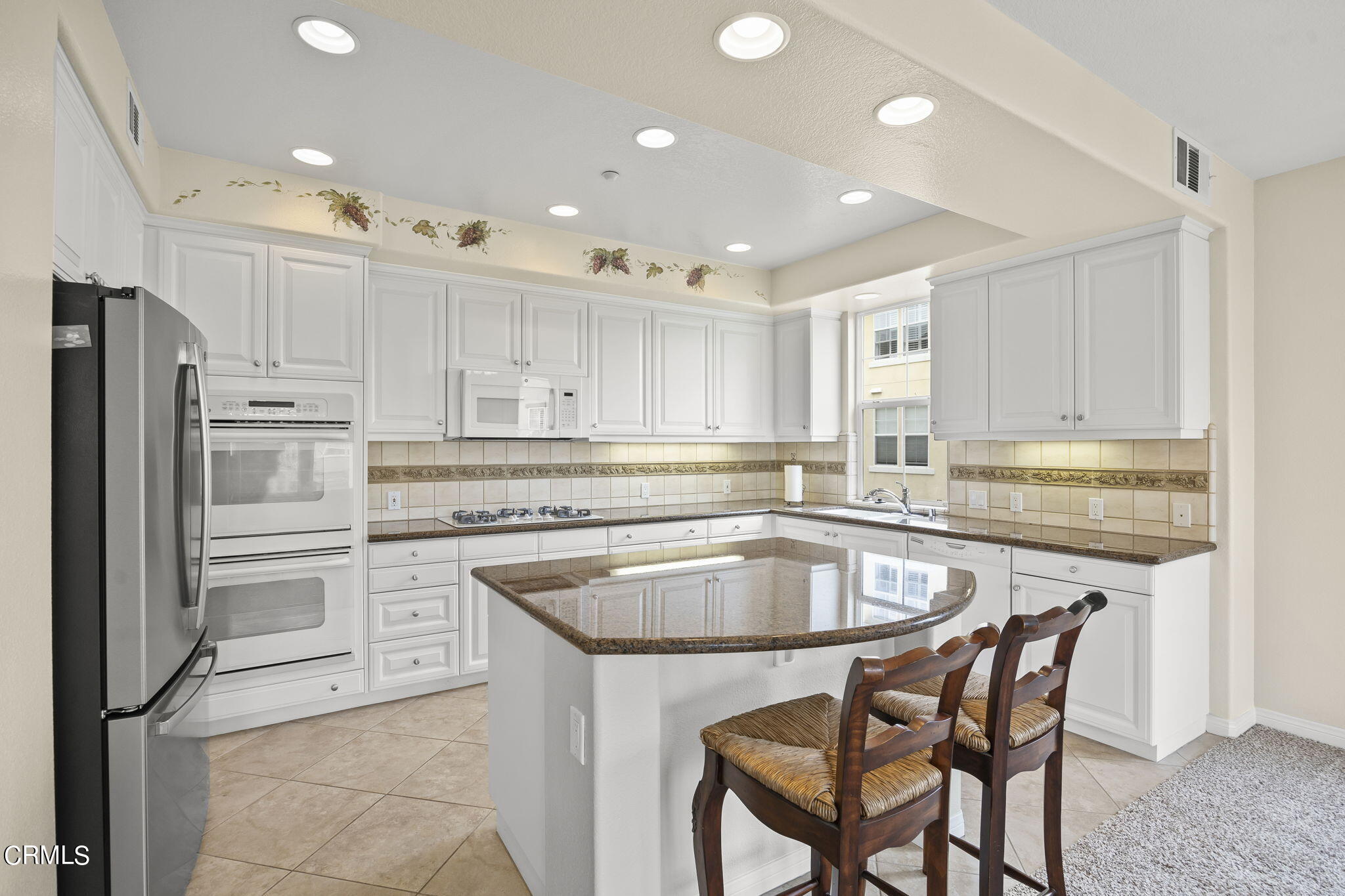 a kitchen with kitchen island granite countertop white cabinets and stainless steel appliances