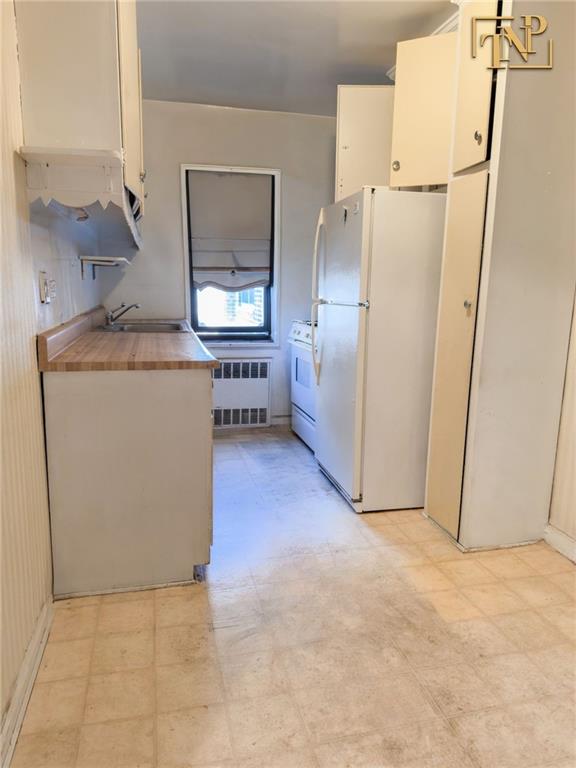 2450 Haring Street, Unit 6D Brooklyn, NY 11235 - Photo 6 of 6 a kitchen with refrigerator and white cabinets