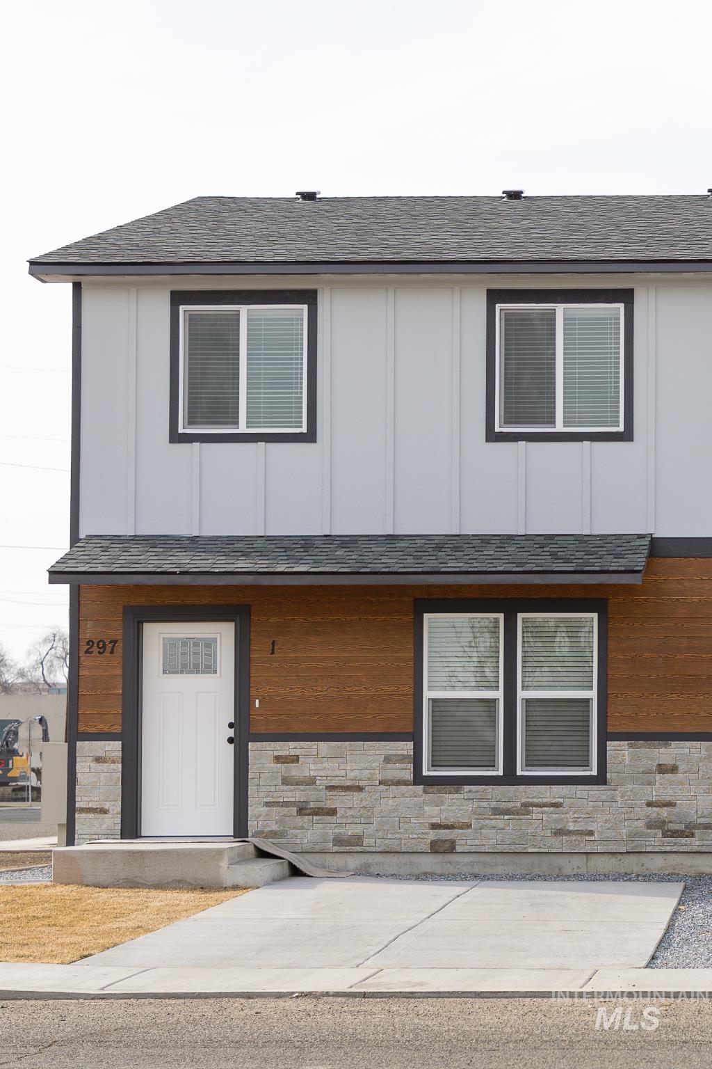 Modern home featuring stone siding, a shingled roof, and board and batten siding