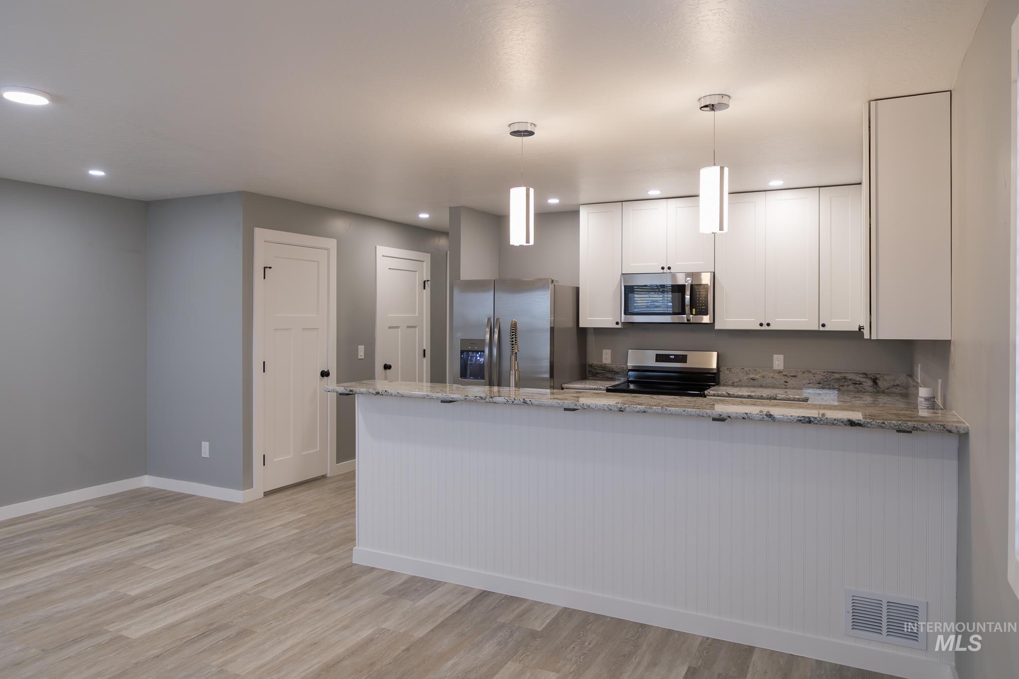 297 Southwest 6th Street, Unit 1 Ontario, OR 97914 - Photo 6 of 50 Kitchen with a peninsula, light stone countertops, white cabinets, and stainless steel appliances