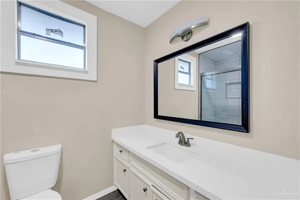 a bathroom with a toilet sink vanity and mirror
