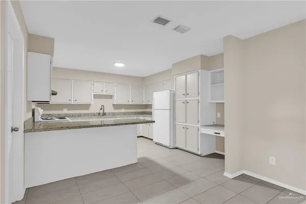 a kitchen with white cabinets and refrigerator