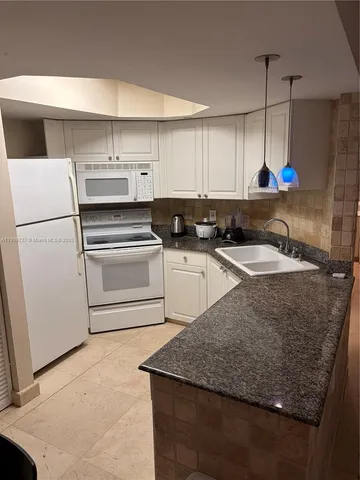 a kitchen with granite countertop white cabinets and white appliances