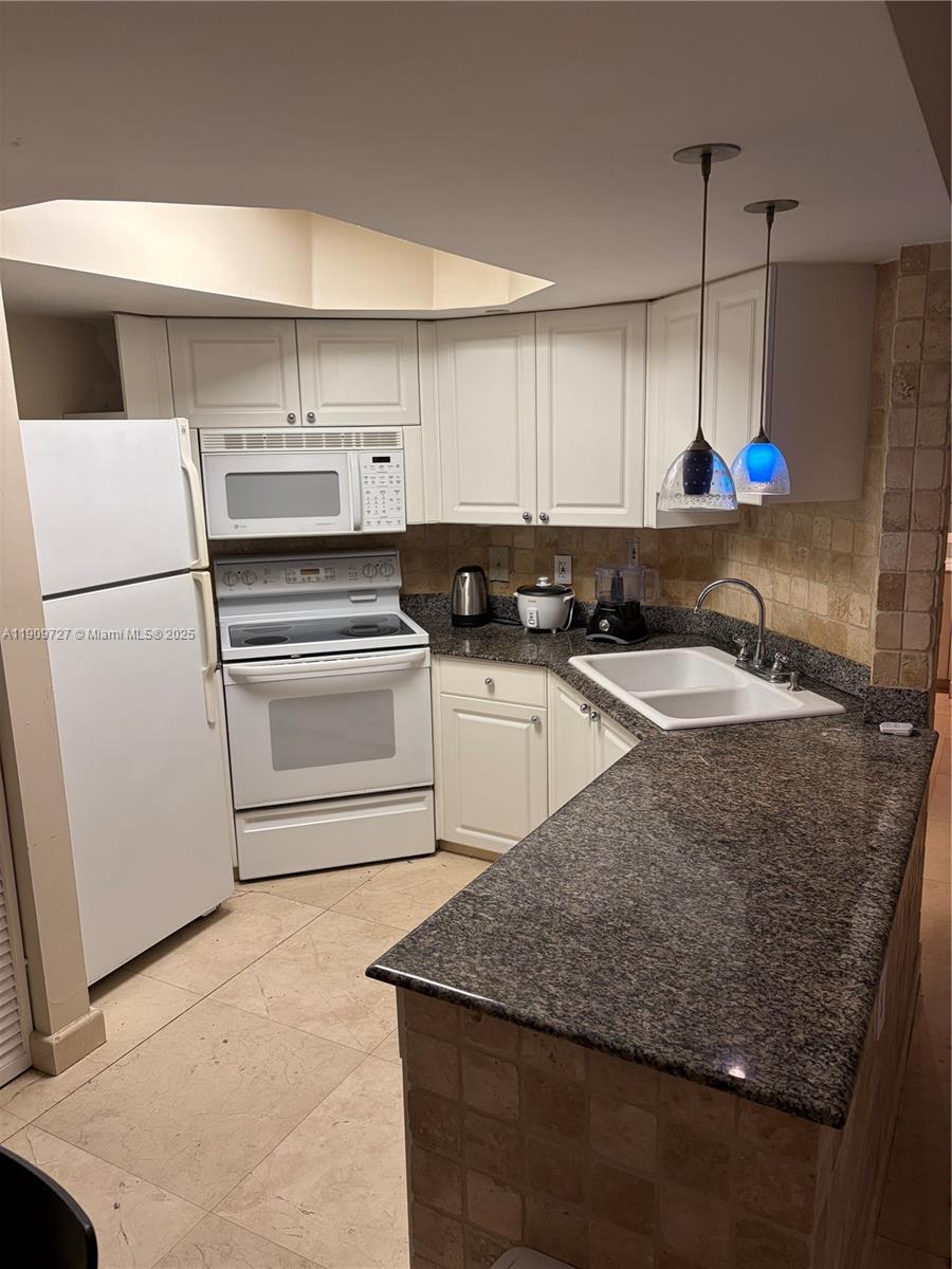 8911 Collins Avenue, Unit 303 Surfside, FL 33154 - Photo 8 of 16 a kitchen with granite countertop a sink a stove and a refrigerator