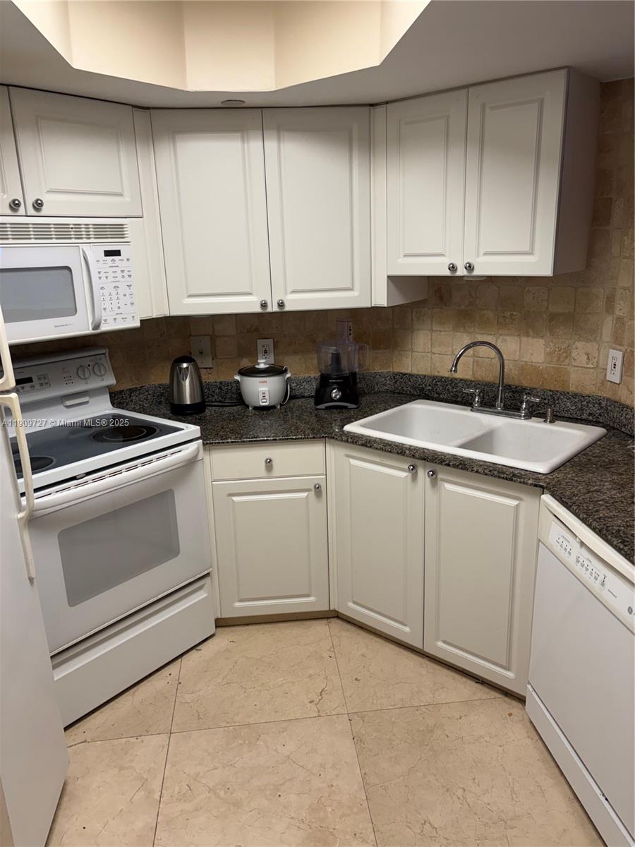 8911 Collins Avenue, Unit 303 Surfside, FL 33154 - Photo 9 of 16 a kitchen with granite countertop white cabinets and white appliances