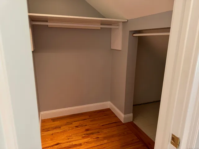 a view of an empty room with wooden floor and closet