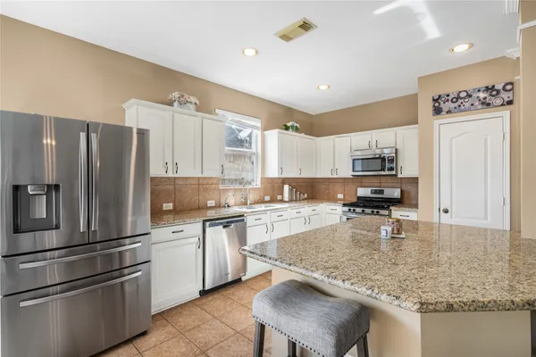 a kitchen with stainless steel appliances granite countertop a sink refrigerator and cabinets