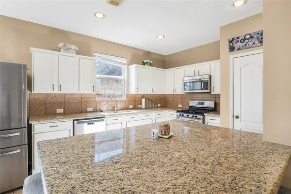 a kitchen with a stove a sink dishwasher a refrigerator and cabinets with wooden floor