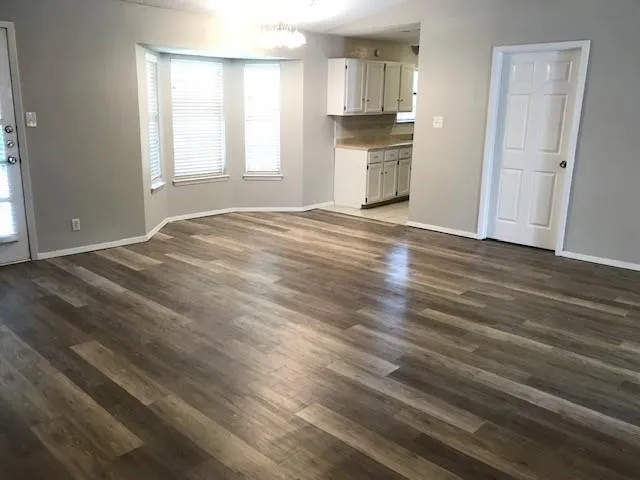 a view of empty room with wooden floor and window