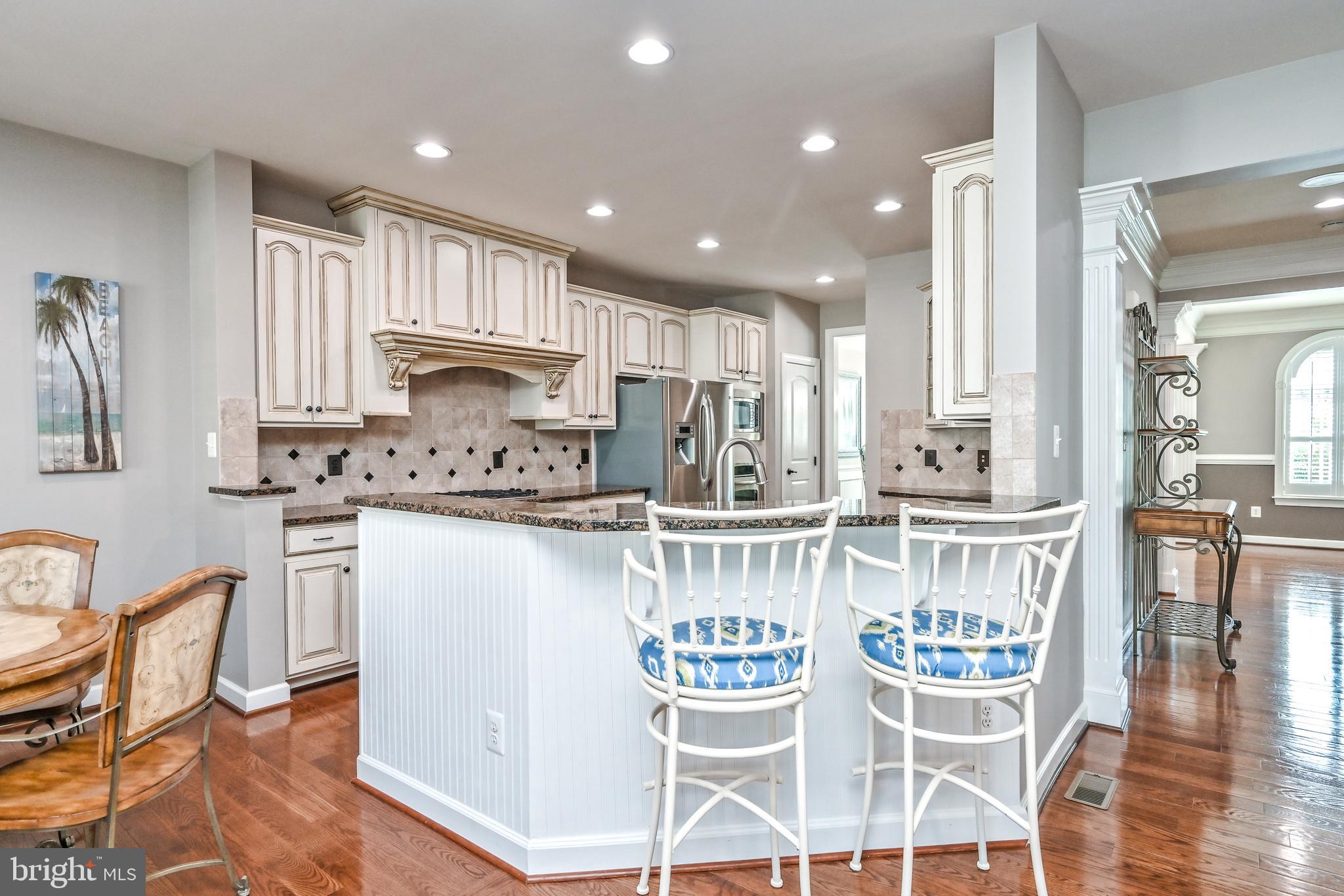 24947 Earlsford Drive Chantilly, VA 20152 - Photo 19 of 40 a kitchen with stainless steel appliances kitchen island granite countertop a dining table chairs and white cabinets