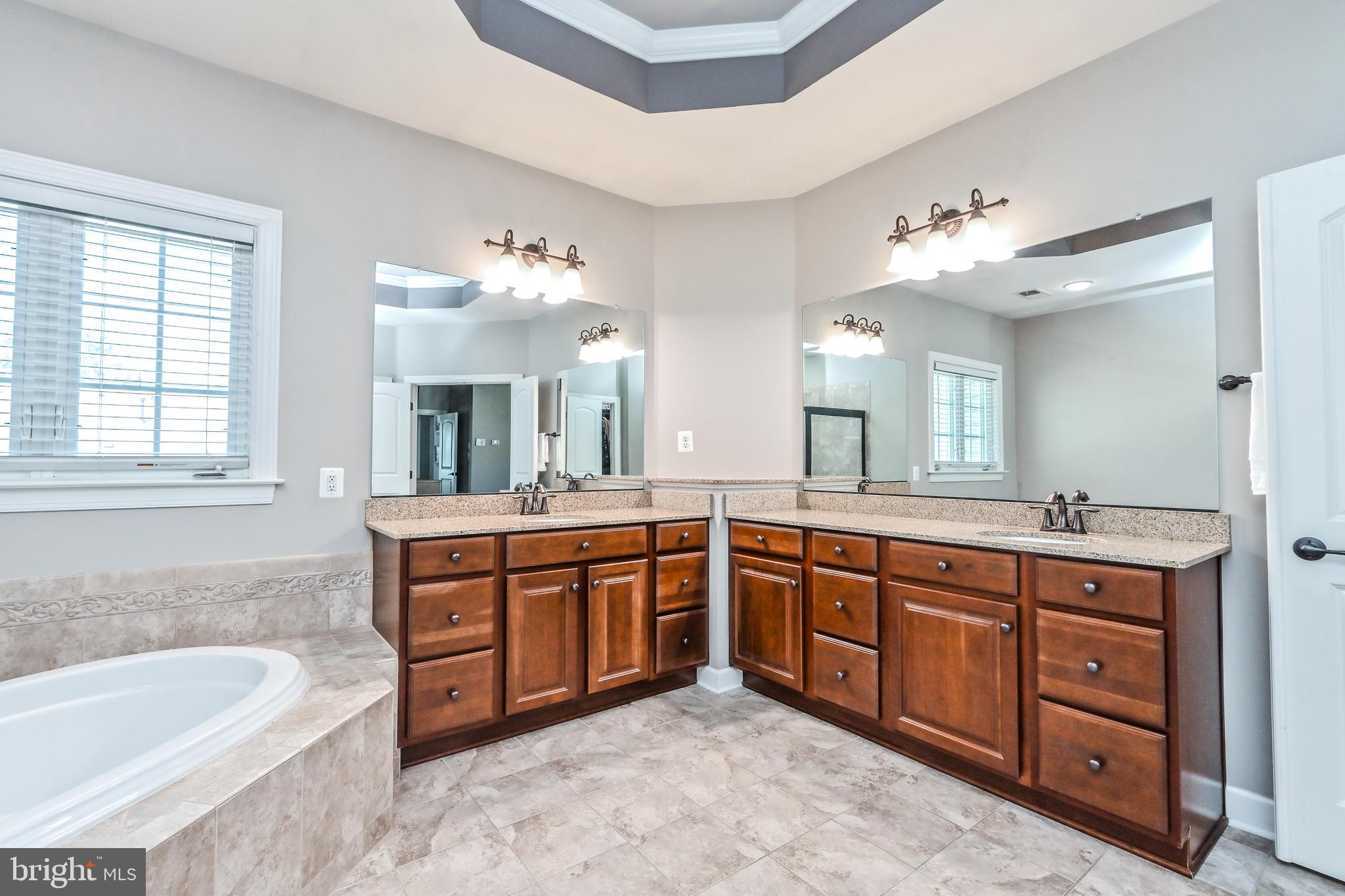 24947 Earlsford Drive Chantilly, VA 20152 - Photo 37 of 40 a spacious bathroom with a granite countertop double vanity sink large mirror bathtub and window