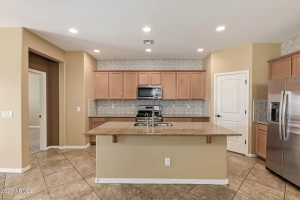 a view of a kitchen with kitchen island stainless steel appliances sink refrigerator and microwave