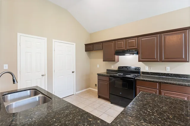 a kitchen with granite countertop a sink stove and refrigerator
