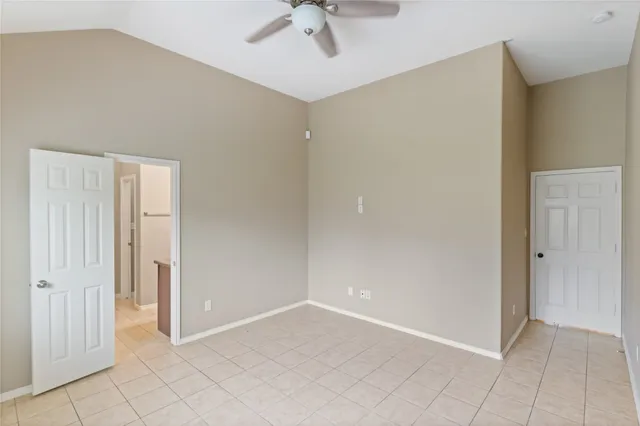 a view of an empty room with window and chandelier fan