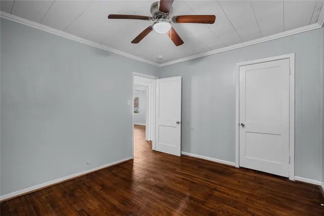an empty room with wooden floor and ceiling fan