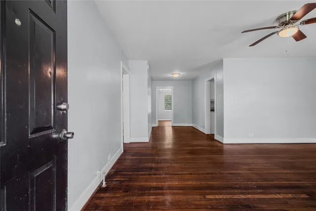 a view of an empty room with wooden floor and a stairs