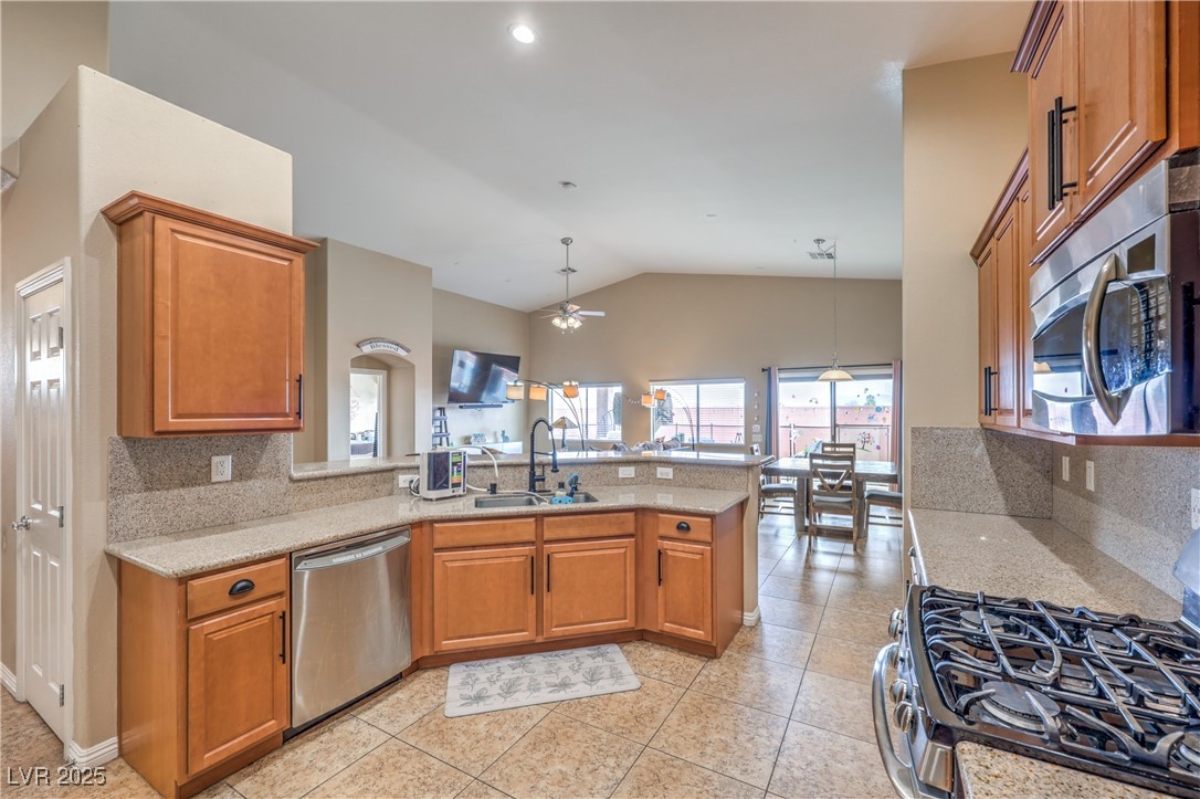 Kitchen with light tile patterned flooring, a sink, a ceiling fan, a peninsula, and stainless steel appliances