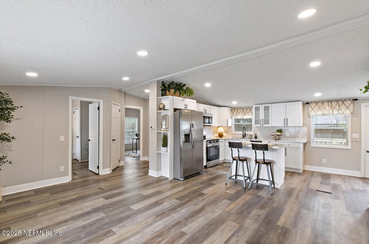 3032 Snell Street Jacksonville, FL 32218 - Photo 4 of 17 a open kitchen with stainless steel appliances kitchen island granite countertop a refrigerator a stove a dining table and chairs with wooden floor