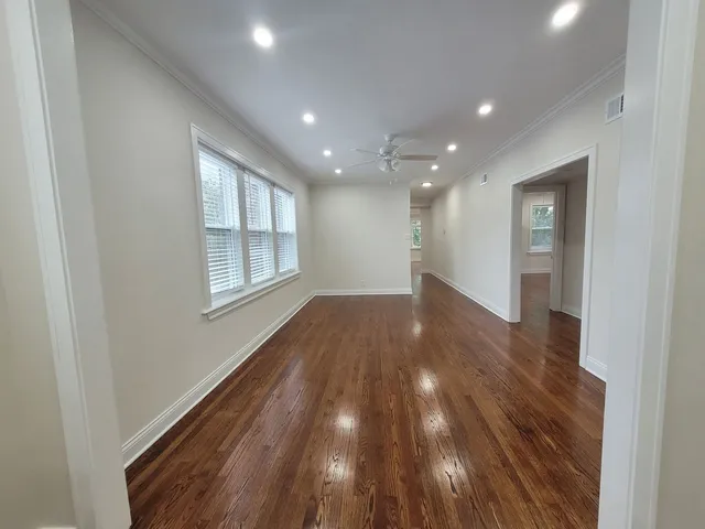 a view of empty room with wooden floor and fan