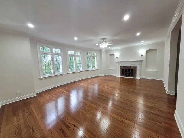 an empty room with wooden floor fireplace and windows