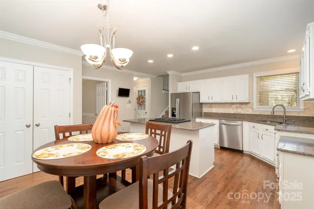a view of a dining room and a kitchen with a table chairs and chandelier