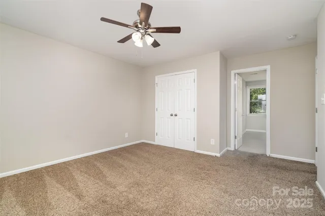an empty room with a chandelier fan and windows