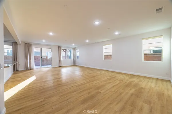 a view of an empty room with window and wooden floor