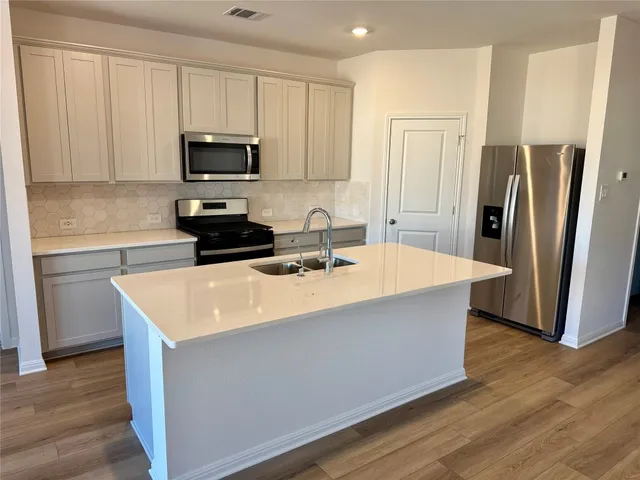 a kitchen with stainless steel appliances a microwave a sink a refrigerator and white cabinets