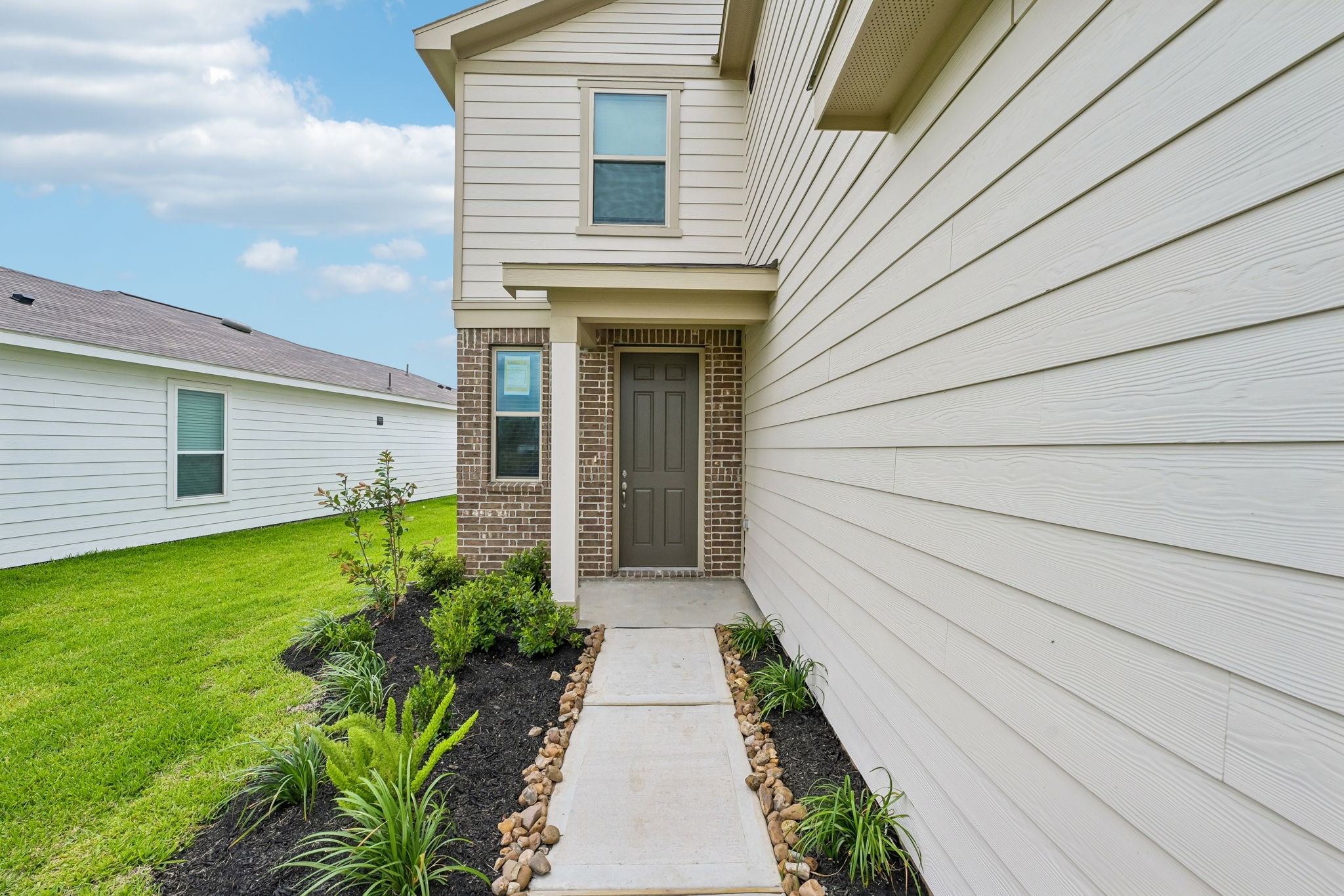 7210 Brooklea Road Beasley, TX 77417 - Photo 4 of 32 A welcoming covered entryway sets the tone with clean architectural lines and contrasting brick, a rich wood front door, and landscaped garden beds that create inviting curb appeal.