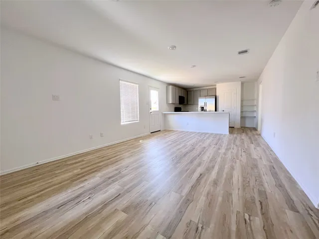 a view of empty room with wooden floor and window
