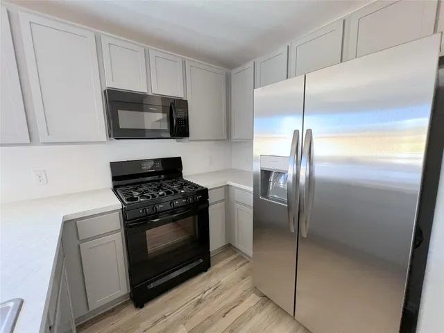 a kitchen with stainless steel appliances wooden floor sink and wooden cabinets