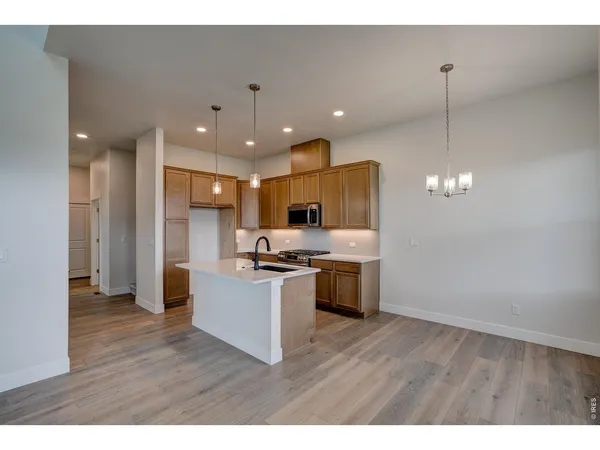 a kitchen with stainless steel appliances granite countertop a refrigerator a sink dishwasher a stove and a wooden floor
