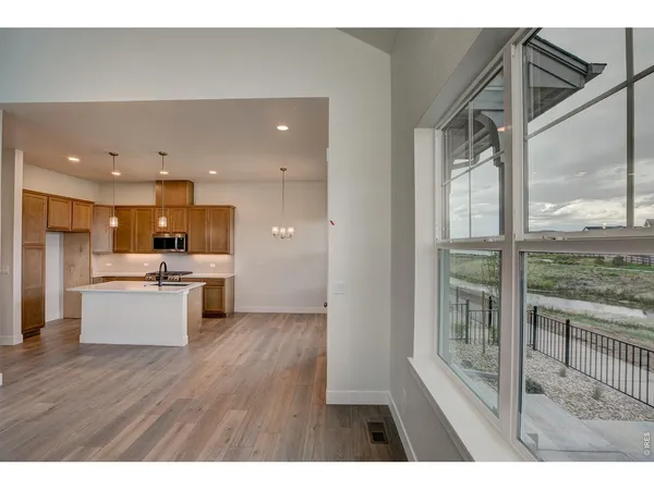 a living room with stainless steel appliances kitchen island granite countertop a stove a sink and a refrigerator with wooden floor