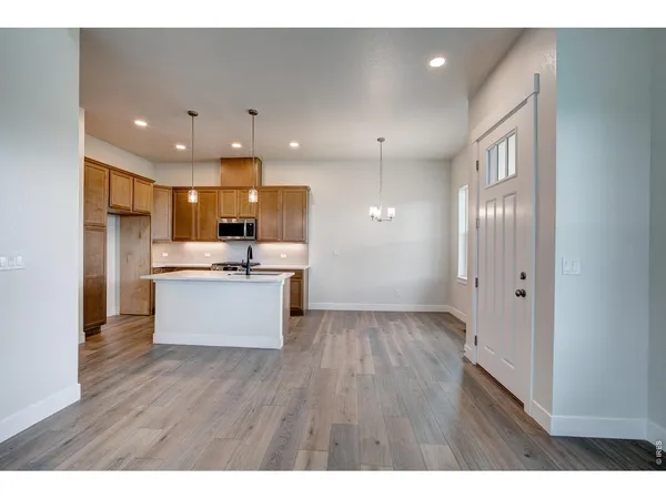 a large kitchen with stainless steel appliances kitchen island a large counter top and wooden floors