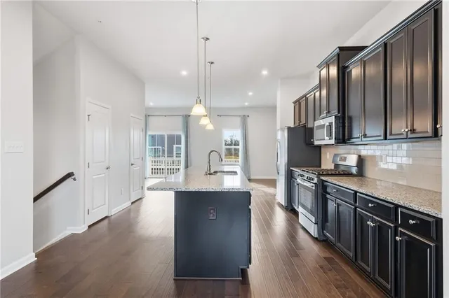 a large kitchen with stainless steel appliances kitchen island granite countertop a large counter top and wooden floors