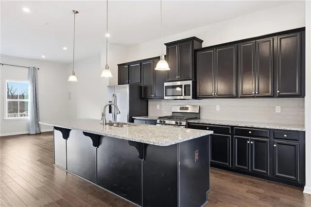 a kitchen with stainless steel appliances granite countertop a sink a stove and refrigerator