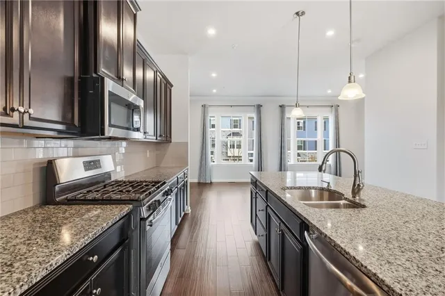 a kitchen with granite countertop stainless steel appliances a sink stove top oven and cabinets