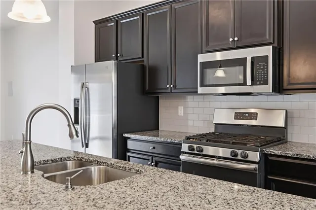 a kitchen with stainless steel appliances granite countertop a stove microwave and sink