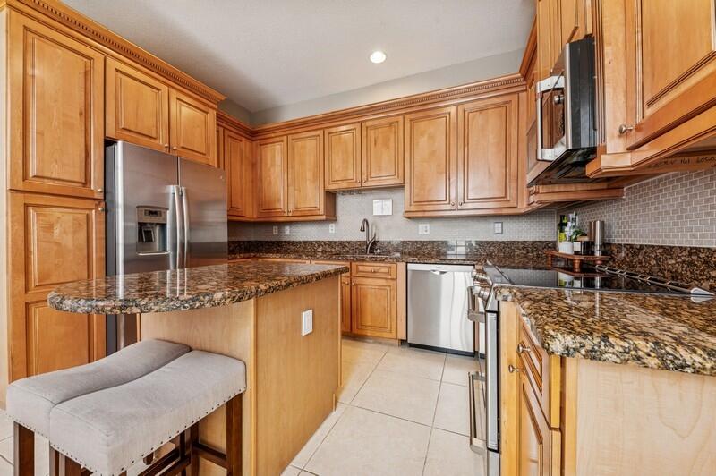 8292 Northwest 9th Avenue Boca Raton, FL 33487 - Photo 6 of 15 a kitchen with stainless steel appliances granite countertop a stove top oven a sink dishwasher a refrigerator and cabinets with wooden floor